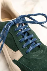 Zapatillas deportivas de gamuza verde con detalles en cuero color crema, cordones blancos y suela chunky color crema.