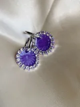 Par de aros colgantes con base de resina violeta y borde de strass plateado, con arito de acero quirúrgico.