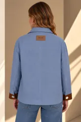 Campera marrón de lino con diseño bicolor, con una franja central gris claro que incluye botones de nácar. Cuenta con cuello alto, mangas largas con puños grises, bolsillos frontales aplicados y silueta amplia.