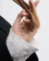 Dije dorado con forma de llave y textura efecto arena, con circonita engarzada.