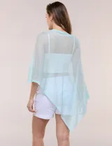 Poncho liviano de tejido de punto fino calado, color blanco, con silueta asimétrica envolvente, escote bote drapeado y mangas integradas estilo capa.