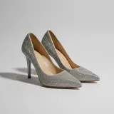 Zapato stiletto de tacón alto con acabado brillante cubierto de pedrería plateada, punta fina y diseño clásico.