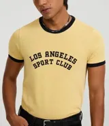 Remera de manga corta estilo ringer, color amarillo claro con ribetes negros en cuello y mangas. Presenta un estampado central en negro con el texto "Los Angeles Sport Club".