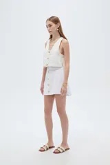 Minifalda de jean blanca de corte recto, con botonera frontal con botones metálicos dorados y costuras pespunteadas a contratono.