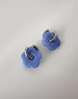 Aros de acero quirúrgico con argolla plateada y dije de flor translúcida en color lila con lunares negros.