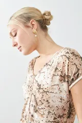 Blusa beige con estampado animal print, escote en V y mangas cortas.