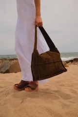 Bolso tipo hobo de cuero marrón con textura acanalada, diseño de paneles cosidos y correa ancha al hombro. Cuenta con interior forrado, bolsillo y llavero incorporado.