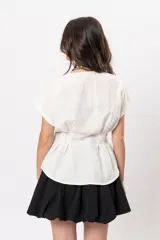 Blusa beige melange con escote en V, manga corta caída, botones metálicos frontales y pinzas que marcan la cintura.