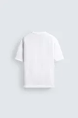 Camiseta de corte relajado confeccionada en algodón con textura irregular, cuello redondo y manga corta.