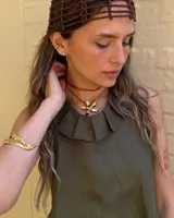 Collar tipo gargantilla con dije de flor metálica de acabado brillante, suspendido de un cordón doble de seda natural teñido a mano en color rojo.