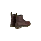 Botas de cuero marrón Dr. Martens 1460 con cordones negros, costuras amarillas características y suela de goma con cámara de aire. Cuentan con forro interior de piel sintética y tirador trasero con el logo de la marca.