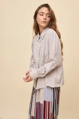 Camisa de manga larga color celeste, con cuello clásico y botonadura frontal. Presenta un calce relajado, con mangas amplias y puños anchos.