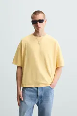 Camiseta gris de corte cuadrado y holgado, con cuello redondo y mangas cortas.