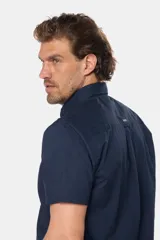 Camisa lisa de manga corta color crema, confeccionada en 100% algodón, con cuello abotonado y un bolsillo en el pecho.