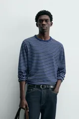 Camiseta de manga larga con cuello redondo y efecto lavado. Presenta un patrón de rayas horizontales finas en azul marino y blanco/beige.