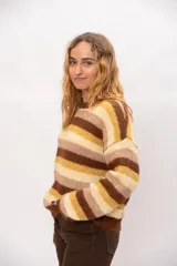 Sweater de punto con diseño de rayas horizontales en tonos tierra, amarillo y crema. Presenta cuello redondo, mangas largas y terminaciones acanaladas en puños y cintura.