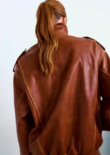 Chaqueta estilo aviador de cuero sintético marrón, con cuello de corderito sintético blanco, bolsillos frontales con solapa, cierre de cremallera y puños y cintura de canalé elástico.