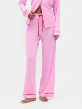 Pantalón de pijama de modal color rosado, con corte recto y holgado. Presenta detalles de vivo en color rojo en el ruedo y cordón de ajuste en la cintura en el mismo tono.