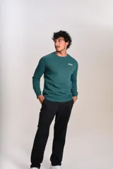 Buzo verde oscuro de cuello redondo, mangas largas con puños elásticos y pequeño estampado ovalado en el pecho.