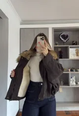 Campera tipo bomber de gamuza en color tostado, con diseño holgado, mangas amplias y cierre frontal con solapa.
