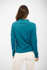 Buzo de tejido de punto fino en color turquesa, con cuello alto y mangas largas. Presenta un corte recto y terminaciones simples en puños y ruedo.