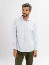 Camisa de vestir de manga larga en color celeste claro, con cuello clásico y cierre frontal de botones. Presenta un diseño de textura sutil y corte regular.