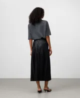 Falda midi negra de efecto piel, con textura arrugada en la parte superior y pliegues amplios en el resto de la falda.