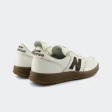 Championes urbanos New Balance, color blanco con la característica "N" y suela en tono marrón oscuro.