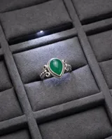 Anillo de plata 925 con piedra natural verde en forma de gota, con detalles ornamentales y grabados en el metal.