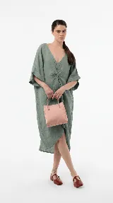 Vestido midi de lino color verde militar, con escote en V, detalle fruncido en el centro del frente y mangas cortas amplias. Posee una silueta relajada y asimétrica.