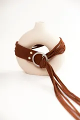 Cinturón de cuero marrón con diseño de flecos largos y argolla metálica plateada como cierre.