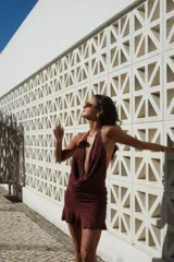 Vestido corto bordó con hilo brillante, escote halter pronunciado y detalle drapeado en el frente. Falda ajustada con fruncidos laterales y terminación con volados.
