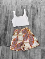 Short de tiro alto con cintura elástica, confeccionado en tela ligera con estampado botánico de hojas en tonos naranja, violeta, beige y blanco.