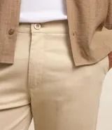 Pantalón de vestir color marrón, de corte slim y largo cropped. Confeccionado en tejido de algodón liso, con bolsillos laterales y traseros. Cierre frontal con botón y cremallera.