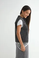 Chaleco de denim acolchado con efecto lavado, diseño sin mangas, cierre frontal y bolsillos laterales.