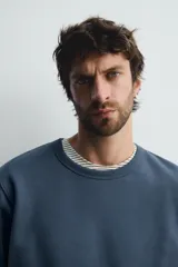Sudadera de corte regular fit, color gris melange, con cuello redondo, manga larga y acabados en rib. Confeccionada en tejido de algodón con interior afelpado.