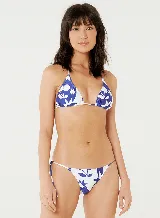 Conjunto de bikini blanco con estampado de cerezas y estrellas en azul. El corpiño es triangular con tirantes finos y la bombacha es cavada con lazos laterales.