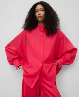 Camisa fucsia amplia y semitransparente, con cuello chimenea, manga japonesa con puño y botonadura frontal oculta.