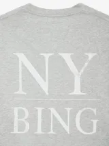 Camiseta gris melange de corte holgado y extragrande, con estampado en el frente con tipografía serif y leyenda 'NY BING' en la espalda.