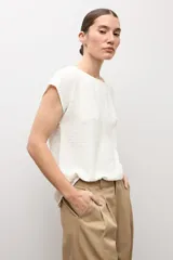 Blusa blanca con textura plumeti, de manga corta y cuello redondo.