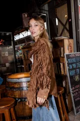 Chaqueta de gamuza marrón con diseño de flecos en la parte delantera y las mangas, corte tipo camisa y cierre frontal de botones.