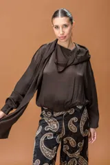 Blusa de tela satinada color marrón oscuro, con cuello drapeado, mangas largas con puños elásticos y ruedo ajustado con elástico.