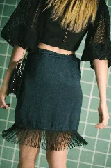 Falda tipo pareo corta, color azul metalizado con acabado brillante y flecos negros decorativos en el borde. Ajustable en la cintura.