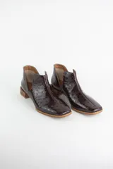 Botin de cuero con acabado grabado efecto avestruz, diseño con aberturas laterales y taco bajo cuadrado.