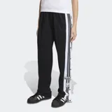 Pantalon deportivo Adidas modelo Adibreak de corte holgado, color negro con franjas laterales blancas y las icónicas tres tiras en negro. Presenta botones a presión a lo largo de los laterales y logo de la marca en la parte inferior.