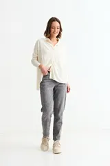 Cardigan de punto color crema, con cuello camisero, cierre frontal de botones y bolsillo frontal en el pecho.