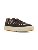 Championes urbanos con diseño de paneles en gamuza marrón y detalles en pelo sintético con estampado animal print de cebra. Presentan suela de plataforma color crema con base de goma y cordones al tono.