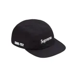 Gorro tipo cap de cinco paneles en color negro, confeccionado con tecnología GORE-TEX. Presenta el logo de Supreme bordado en un parche rectangular en la parte frontal y la inscripción GORE-TEX bordada en el lateral.