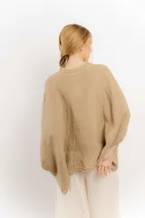 Camisa color crema de lino con mangas amplias y cinta en tono más oscuro en el cuello y la botonadura.