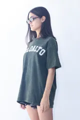 Remera verde con efecto gastado, corte oversize y estampado frontal con la palabra 'DELOALTO' en blanco.